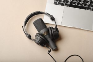 Mikrofons un austiņas uz klēpjdatora fona podkāsta ierakstam