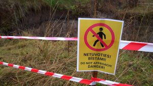 Brīdinājuma zīme ar uzrakstu “Netuvoties! Bīstami!” pie nogruvuma, norobežota ar sarkanbalto lenti.