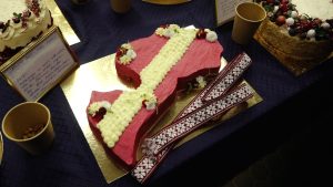 Torte Latvijas kontūras formā ar sarkanbaltsarkanu dekoru un tautisku jostu.
