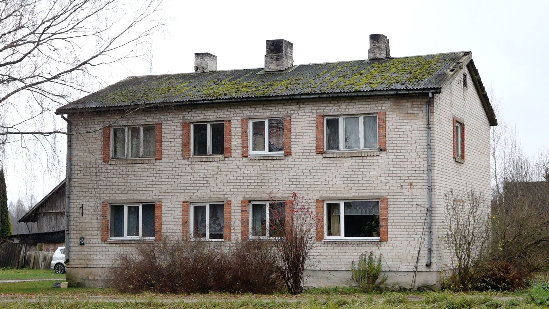 Vecāka divstāvu daudzdzīvokļu māja no gaišiem ķieģeļiem un šīfera jumtu.