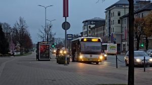 Autobuss pie pieturas Jelgavā agrā rītā ar izgaismotu maršruta numuru.