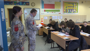 Valsts aizsardzības mācības instruktori klasē ar skolēniem, kas raksta.