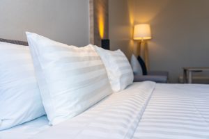 Baltas gultas veļa ar spilveniem viesnīcas numuriņā