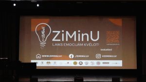 ZiMinU pasākuma lielais ekrāns ar projekta logo, saukli un informāciju.