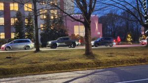Agrā rīta stundā pie skolas ēkas, kas rotāta ar svētku gaismiņām, privātās automašīnas izlaiž skolēnus.