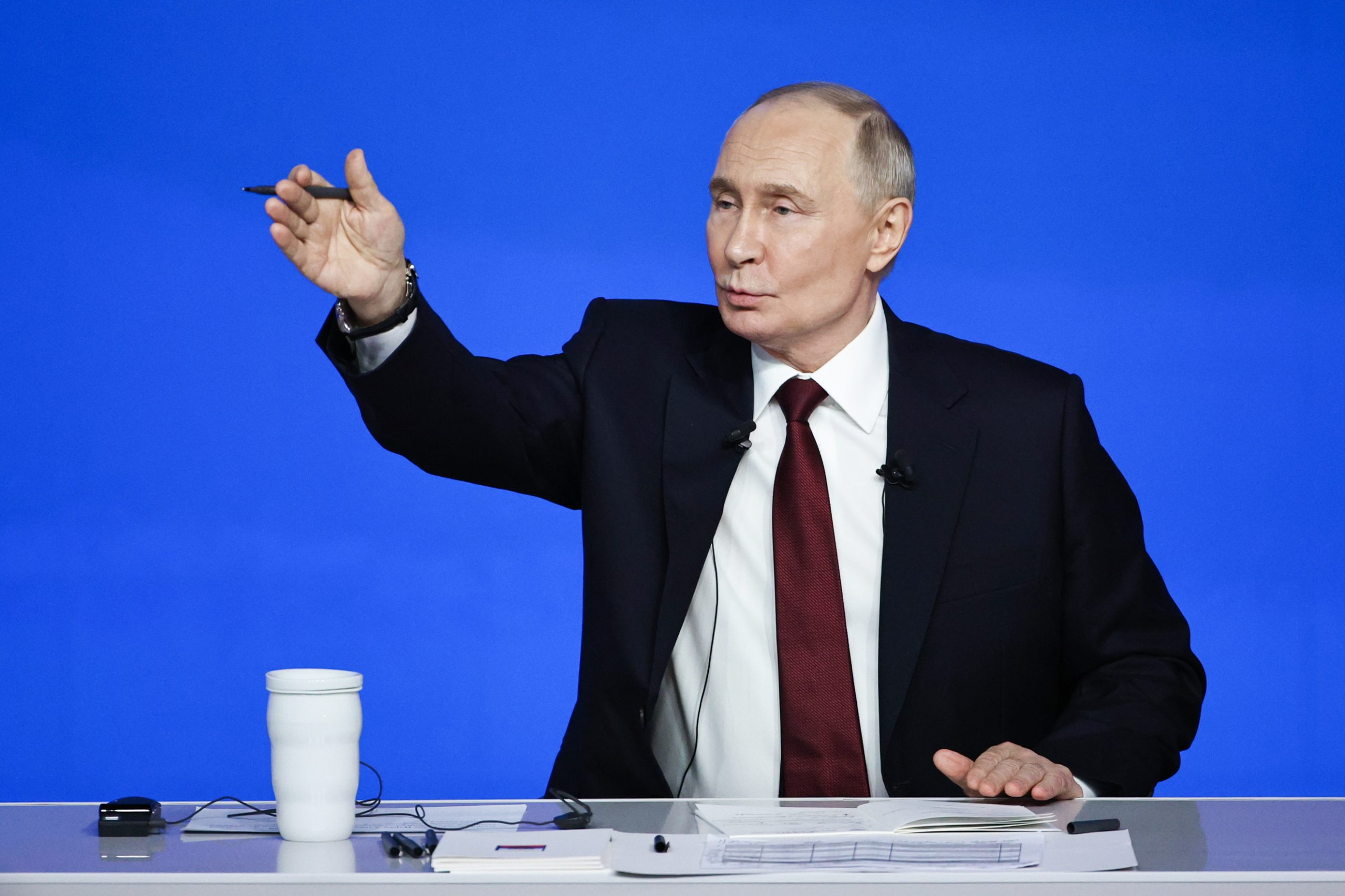 Krievijas prezidents Vladimirs Putins uzstājas preses konferencē pie galda uz zilas fona sienas.