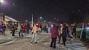 Ziemassvētku skrējiena dalībnieki pulcējas ziemīgā vakarā pilsētas parkā