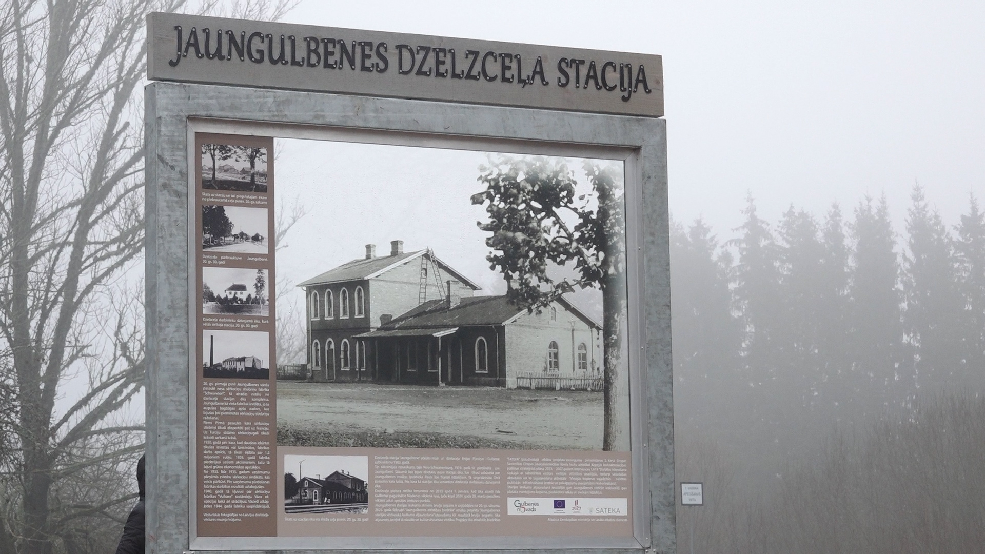 Informācijas stends par Jaungulbenes dzelzceļa staciju ar vēsturisku fotogrāfiju.