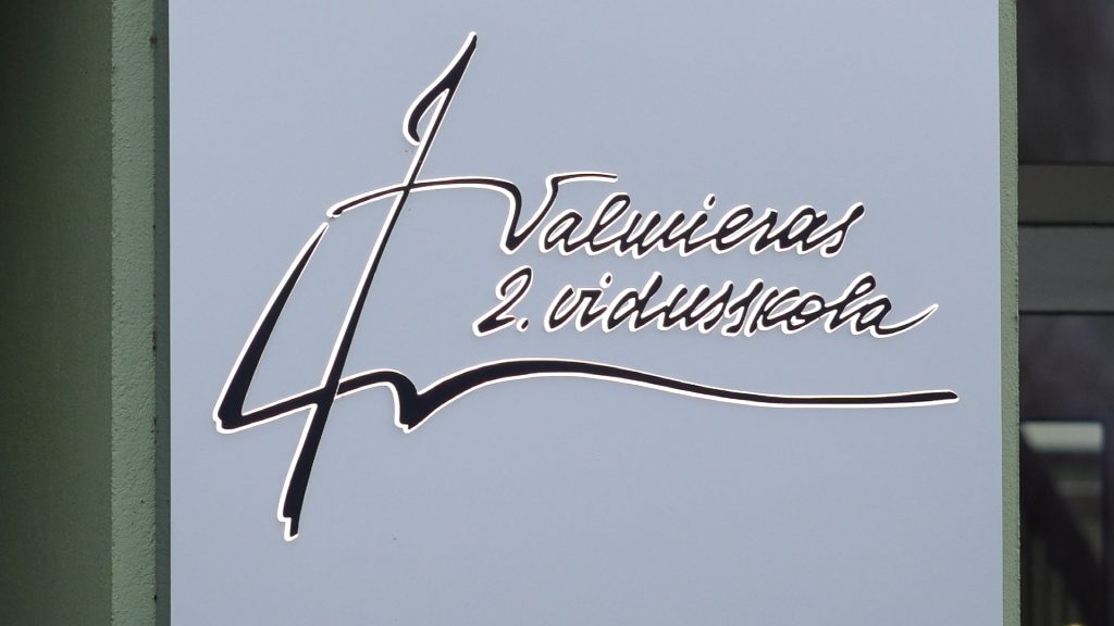Valmieras 2. vidusskolas nosaukuma un logotipa tuvplāns uz skolas sienas.