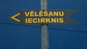 Norādes zīme ar uzrakstu “Vēlēšanu iecirknis” un bultiņu pa kreisi