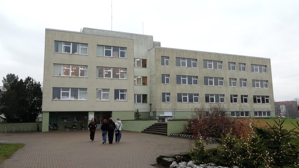 Valmieras 2. vidusskolas liela, gaiša ēka ar daudziem logiem, pie ieejas stāv vairāki cilvēki.