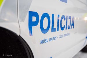 Tuvplāns ar uzrakstu "POLICIJA" un devīzi "MŪSU DARBS - JŪSU DROŠĪBAI" uz automašīnas sāna ziemā.