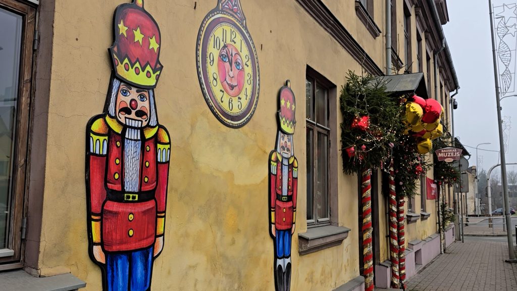 Bauskas muzeja ārsiena ar rotājumiem – divām lielām Riekstkoža figūrām un saules pulksteņa zīmējumu.