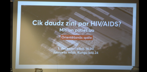 Projekcija uz sienas ar pasākuma paziņojumu: "Cik daudz zini par HIV/AIDS? Mīti un patiesība. Orientēšanās spēle. 1. decembrī plkst. 16.00 Jauniešu mājā, Kungu ielā 24".