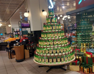 Ziemassvētku egle no alkoholiskā dzēriena pudelēm tirdzniecības centrā, kas ilustrē alkohola tirdzniecības veicināšanu svētku laikā