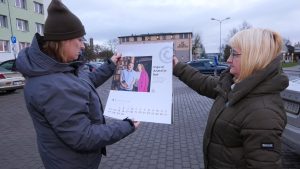 Divas sievietes pilsētvidē tur kalendāru ar Ingas un Anatolija Bali portretu.