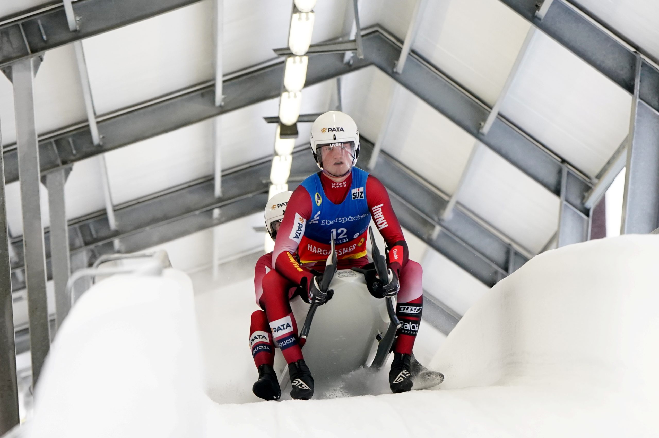 Latvijas kamaniņu sporta divnieks pilnā ātrumā traucas pa Siguldas trasi sacensību laikā.