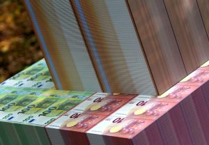 Milzīgas eiro banknošu ķīpas (100 un 10 eiro nomināli) sakrautas cieši viena pie otras.