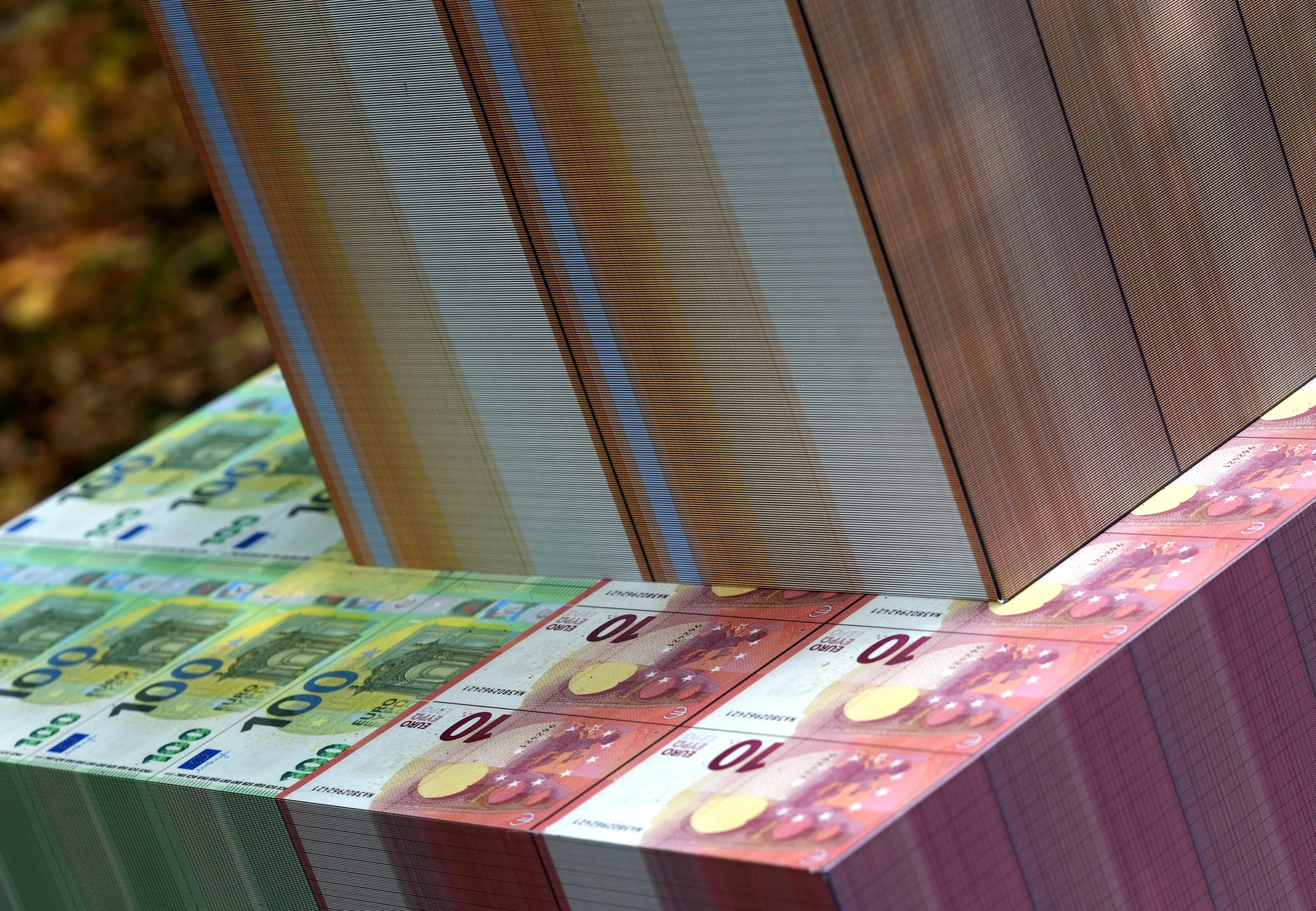 Milzīgas eiro banknošu ķīpas (100 un 10 eiro nomināli) sakrautas cieši viena pie otras.