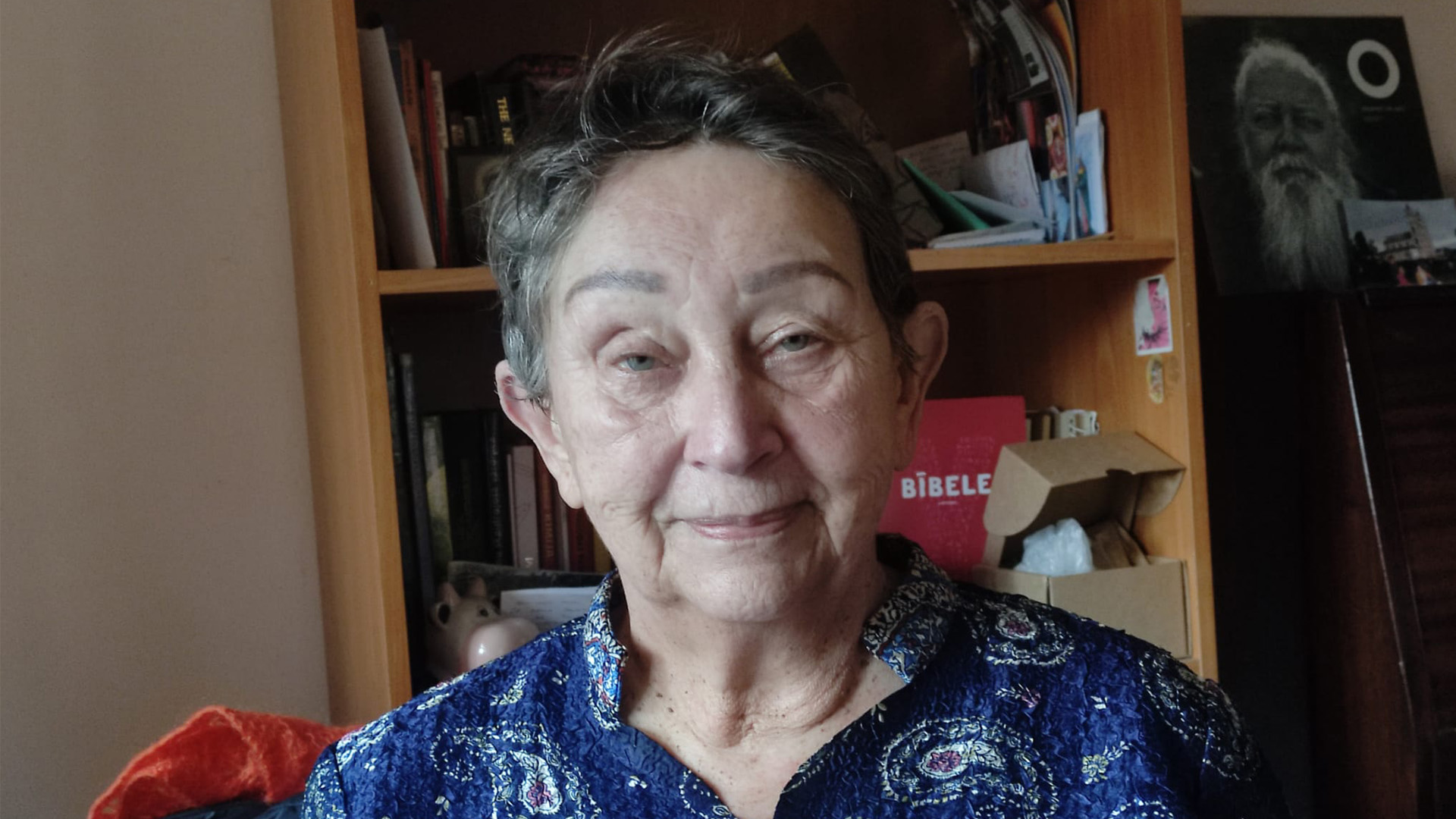 Kuldīgas homeopāte Mārīte Merga savā darba telpā pie grāmatplaukta.