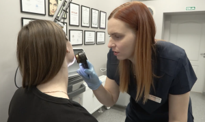 Dermatoloģe pārbauda pacientes ādu ar dermatoskopu medicīnas kabinetā.
