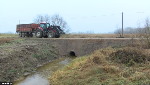 Izskalots ceļa posms Augšdaugavas novadā ar atjaunotu caurteku, pa ceļu brauc traktors pēc vasaras lietavu postījumiem.