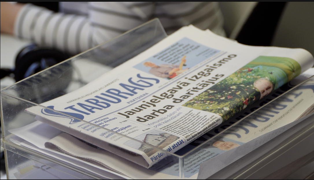 Laikraksts “Staburags” preses piegādes kastē, ilustrējot reģionālo mediju pieejamību un preses izplatīšanu Latvijā.