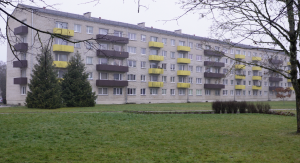 Daudzdzīvokļu dzīvojamā māja ar balkoniem un zaļo zonu priekšplānā