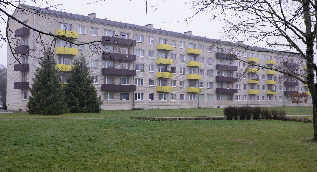 Daudzdzīvokļu dzīvojamā māja ar balkoniem un zaļo zonu priekšplānā