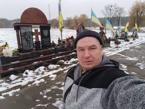 Latviešu brīvprātīgais Ukrainā pie karā kritušo karavīru kapiem ar Ukrainas karogiem.