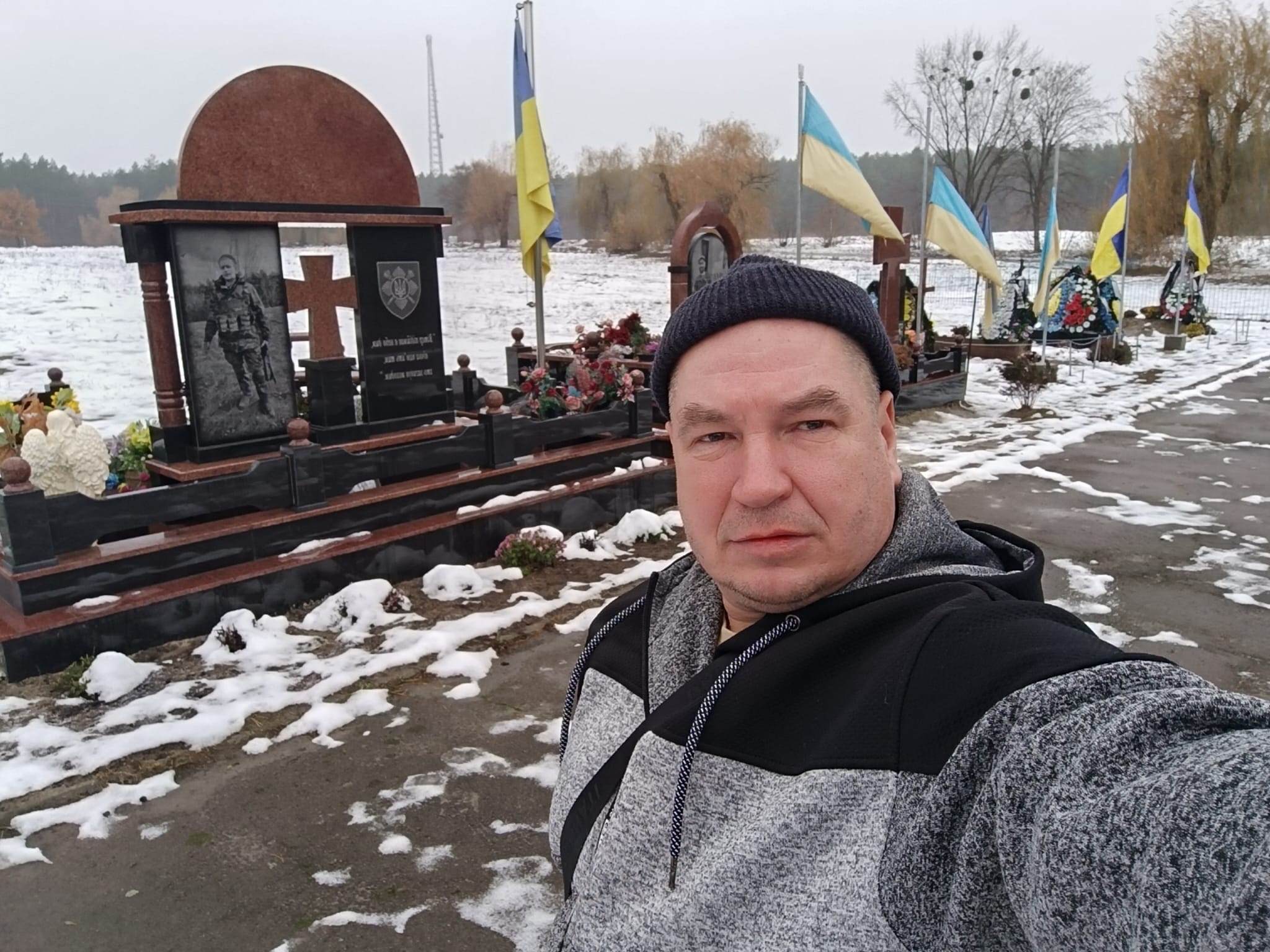 Latviešu brīvprātīgais Ukrainā pie karā kritušo karavīru kapiem ar Ukrainas karogiem.