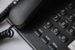Galda vadu telefons ar ciparu tastatūru un klausuli tuvplānā.