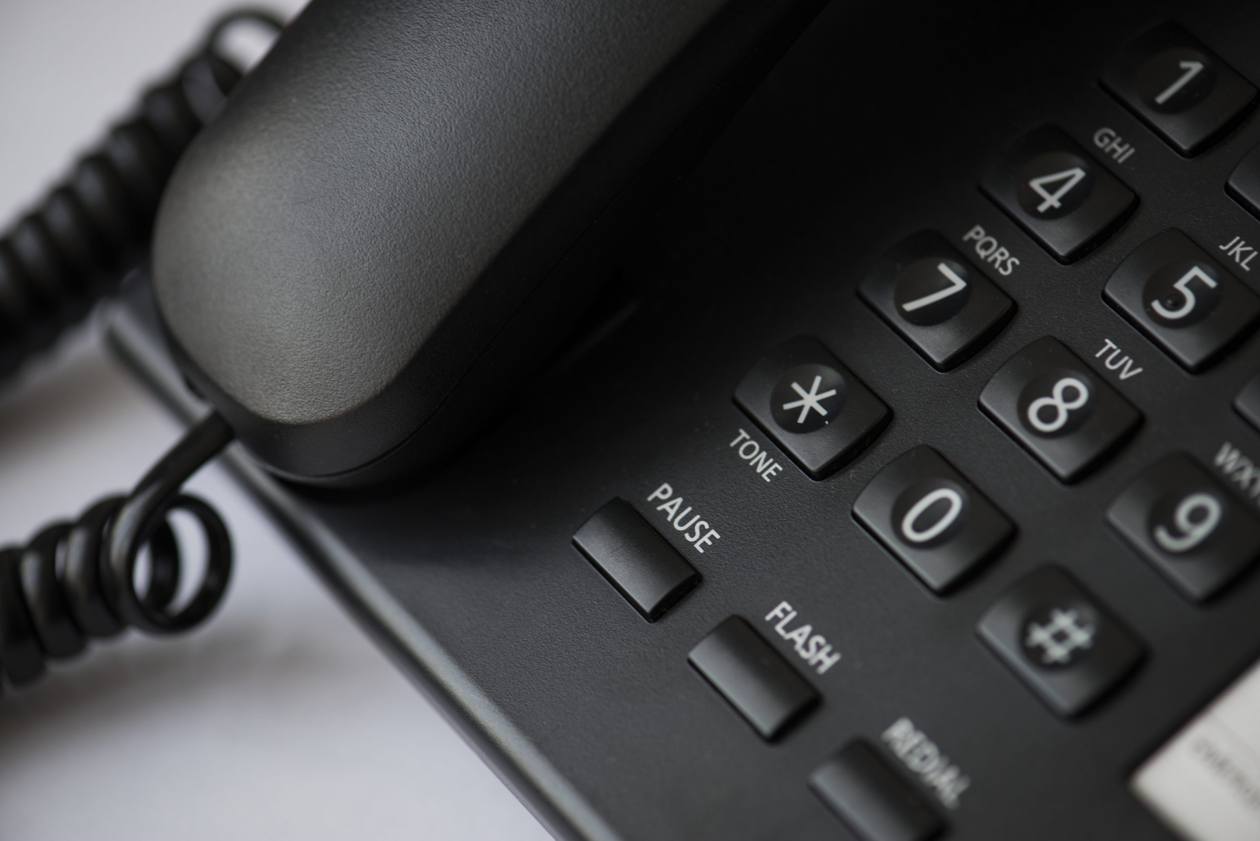 Galda vadu telefons ar ciparu tastatūru un klausuli tuvplānā.