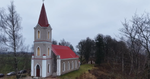 Seces evaņģēliski luteriskā baznīca ar sarkanu torni un jumtu.