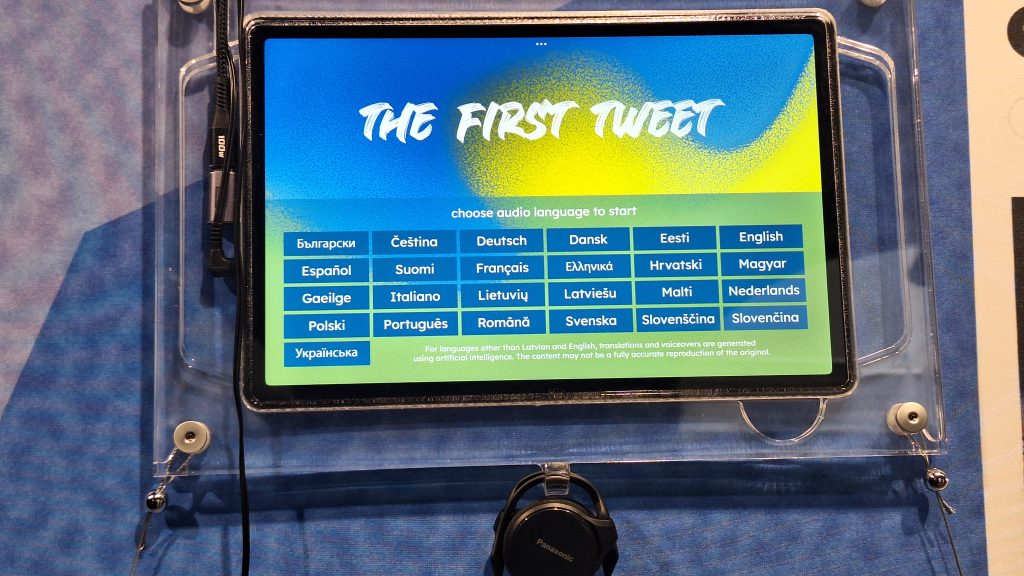 Planšetdators ar uzrakstu "THE FIRST TWEET" un iespēju izvēlēties audio valodu.