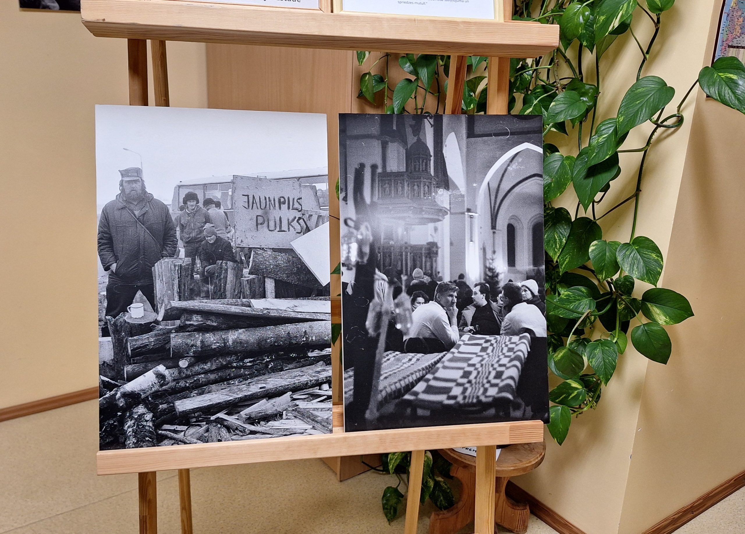 Barikāžu laika melnbaltas fotogrāfijas izstādē Sērenes pagasta bibliotēkā, redzami cilvēki un barikāžu ugunskura malkas krāvums.