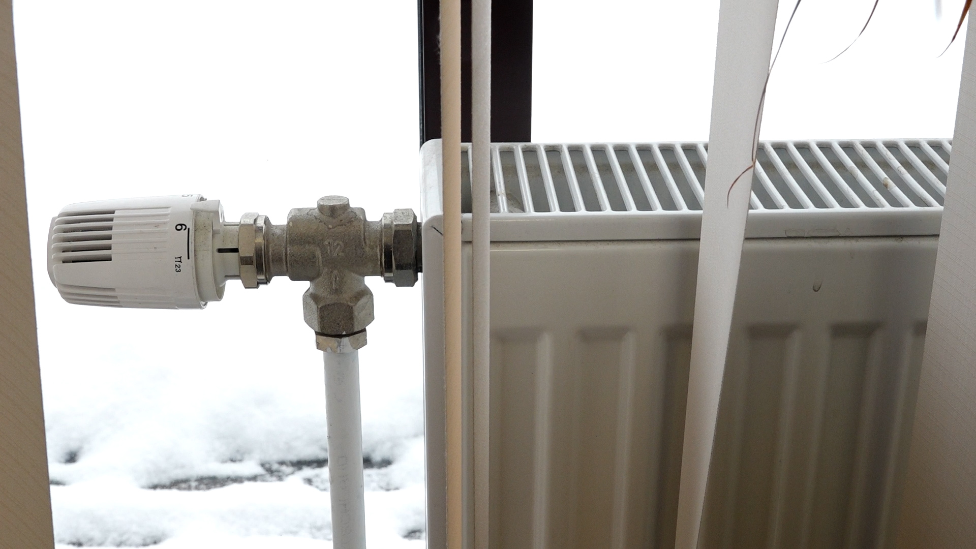 Apkures radiators ar termoregulatoru pie loga ziemas laikā