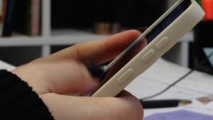 Cilvēks viedtālrunī lasa informāciju sociālajos tīklos, saskaroties ar iespējamu dezinformāciju