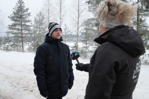 Intervija uz ielas Madonā ziemā – žurnāliste ar mikrofonu sarunājas ar vietējo iedzīvotāju