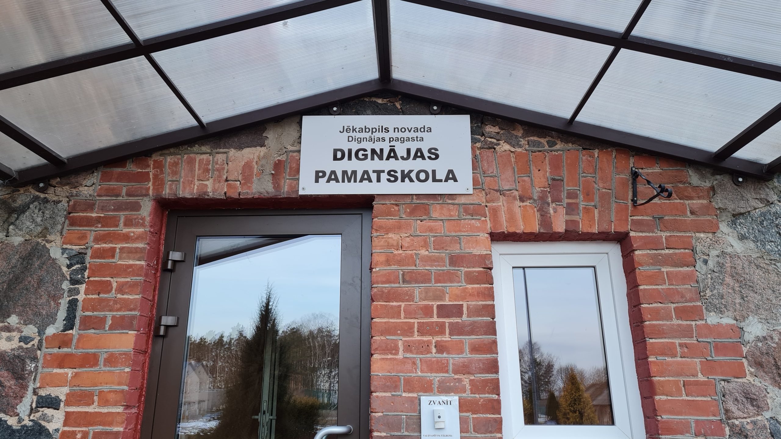 Dignājas pamatskolas ēkas ieeja ar nosaukuma zīmi Jēkabpils novadā