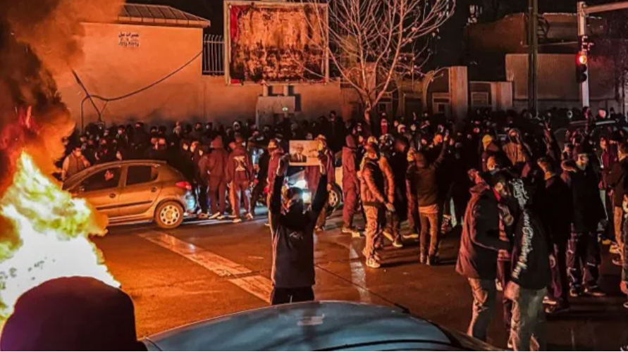 Masu protesti Irānā naktī – cilvēku pūlis ielās, degoša automašīna un sadursmes ar drošības spēkiem.