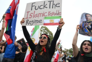 Protestētāji ar Irānas karogiem demonstrācijā tur plakātu ar pret režīmu vērstu vēstījumu.