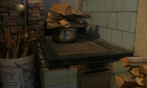 Malkas plīts ar katlu un sagatavotu malku tradicionālā lauku virtuvē