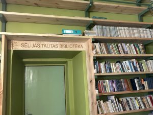 Sēlijas Tautas bibliotēkas ieeja ar koka plauktiem un grāmatām