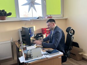 Pašvaldības darbinieks birojā pie datora strādā ar dokumentiem ikdienas darba procesā