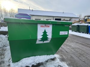 Zaļš konteiners Ziemassvētku eglītēm Jēkabpils novadā pie daudzdzīvokļu mājām ziemā
