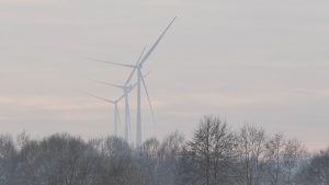 Vēja turbīnas Zemgales ainavā miglainā laikā.