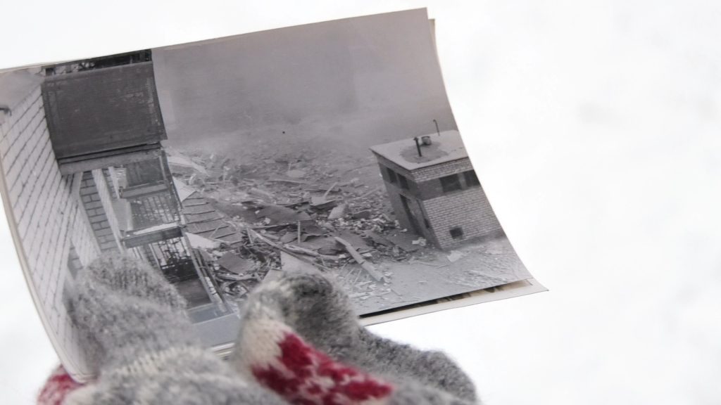 Melnbalta arhīva fotogrāfija ar pilnībā sagruvušu ēkas daļu un gruvešu kaudzi pēc eksplozijas.