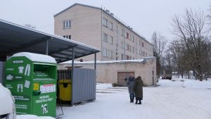 Daudzdzīvokļu mājas pagalmā izvietots tekstila šķirošanas konteiners ziemā