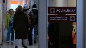 Pacienti Saldus poliklīnikas gaitenī pie norādes “Poliklīnika”